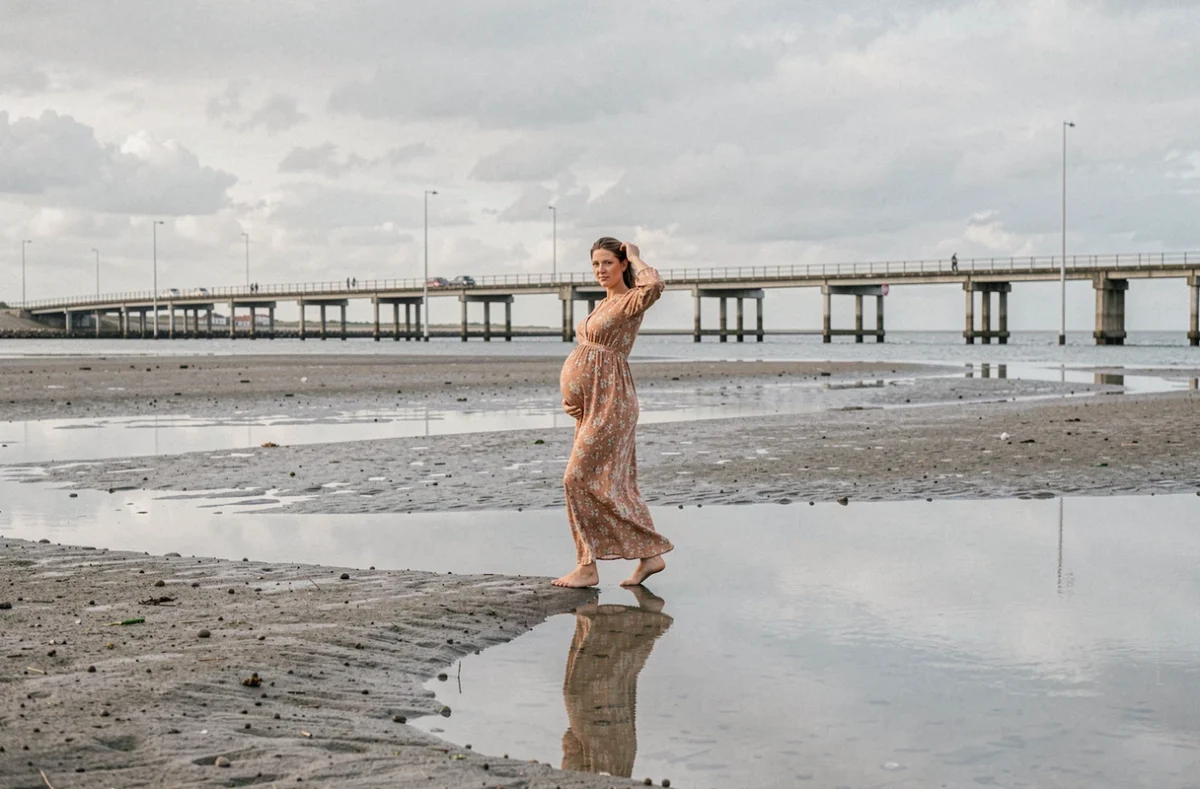 Femme enceinte en robe fleurie marchant pieds nus sur les vasières près du pont de l'Île de Ré à La Rochelle